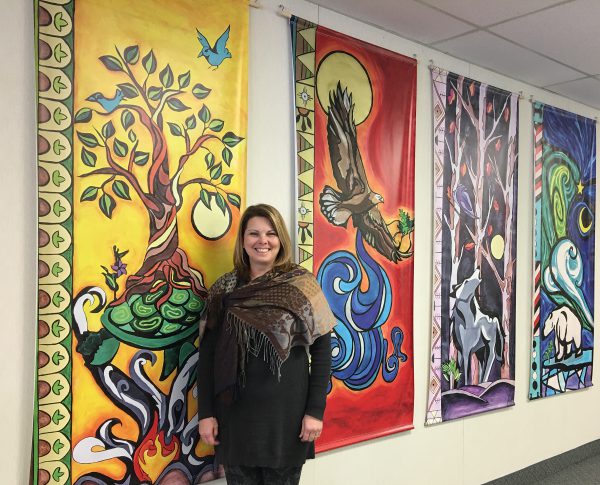 Marian Lawson MacDonald stands with the Board Indigenous banners