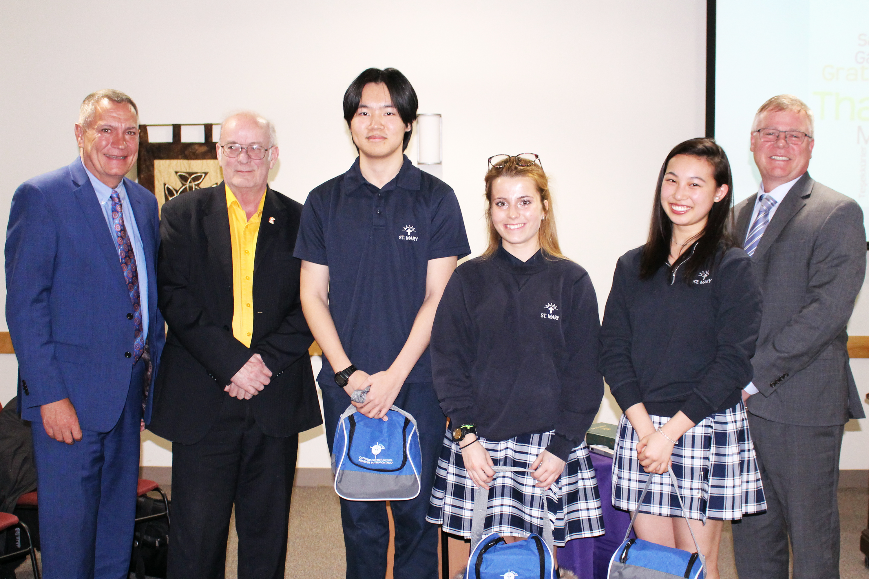 Three international students stand with the trustee, chair, and director of education at the CDSBEO board meeting on March 19.