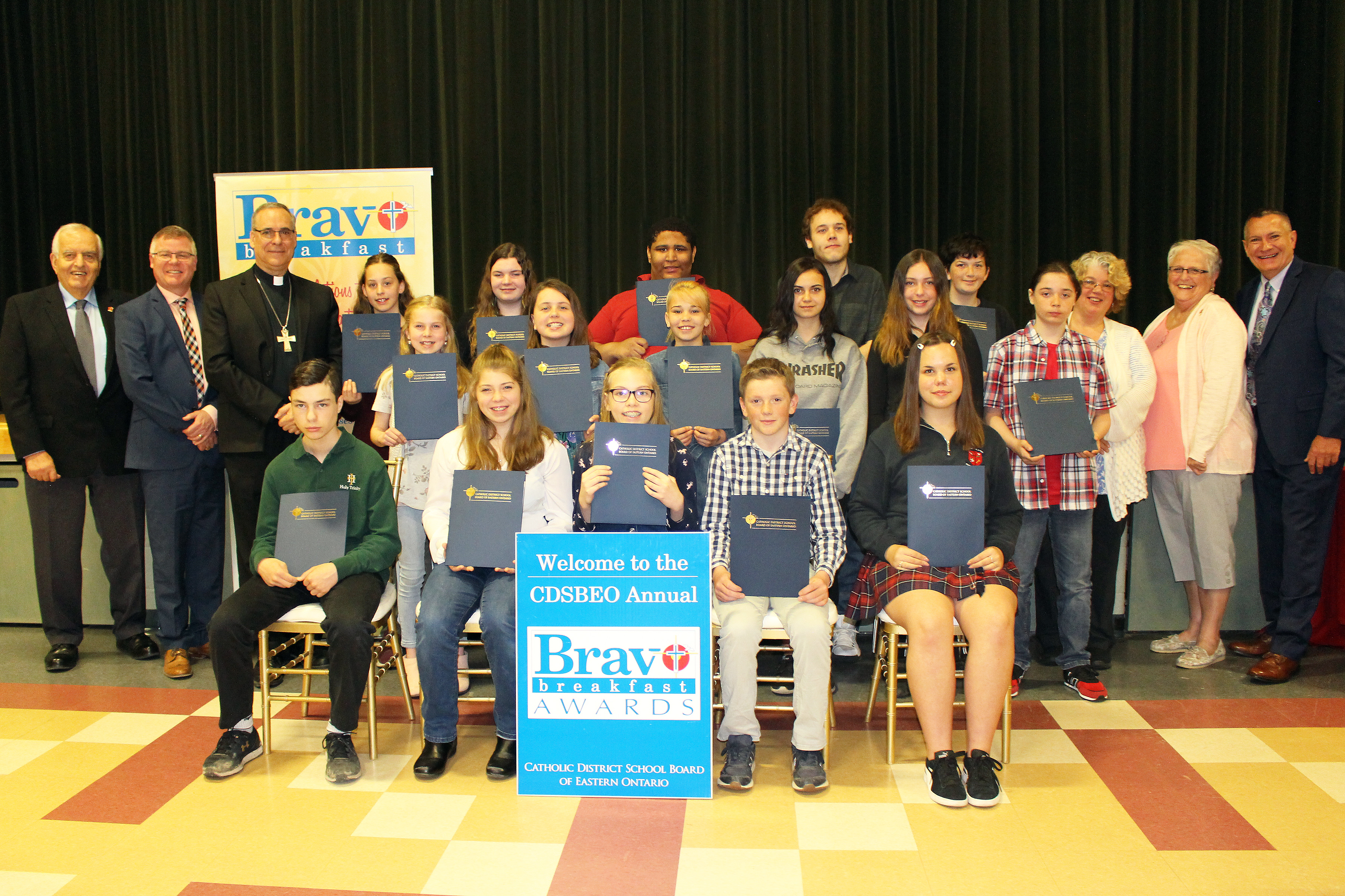 Students stand with their awards, along with board trustees, administrators, and Bishop Desroches.