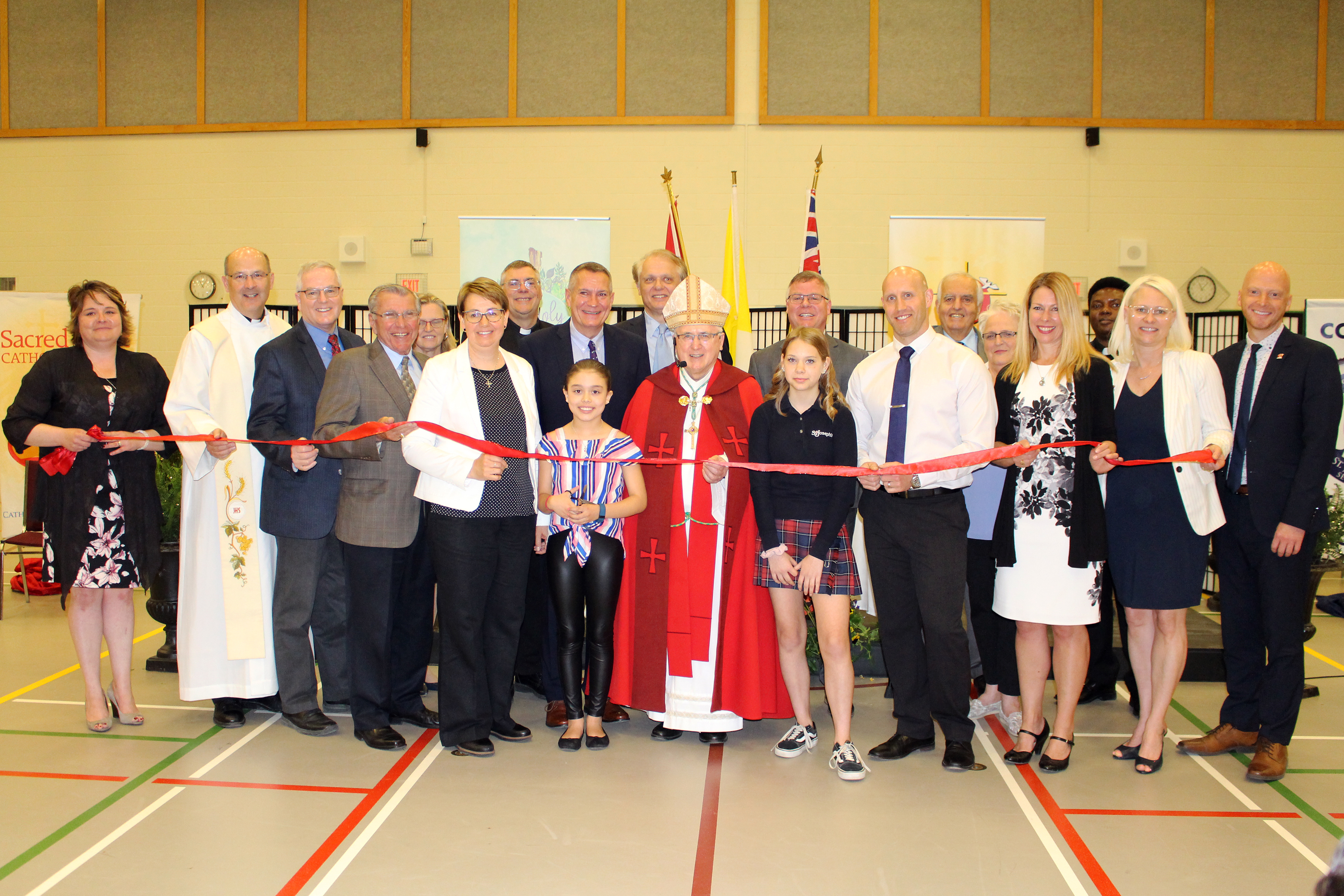 A group of students, staff, clergy and dignitaries stand for the official ribbon cutting ceremony.