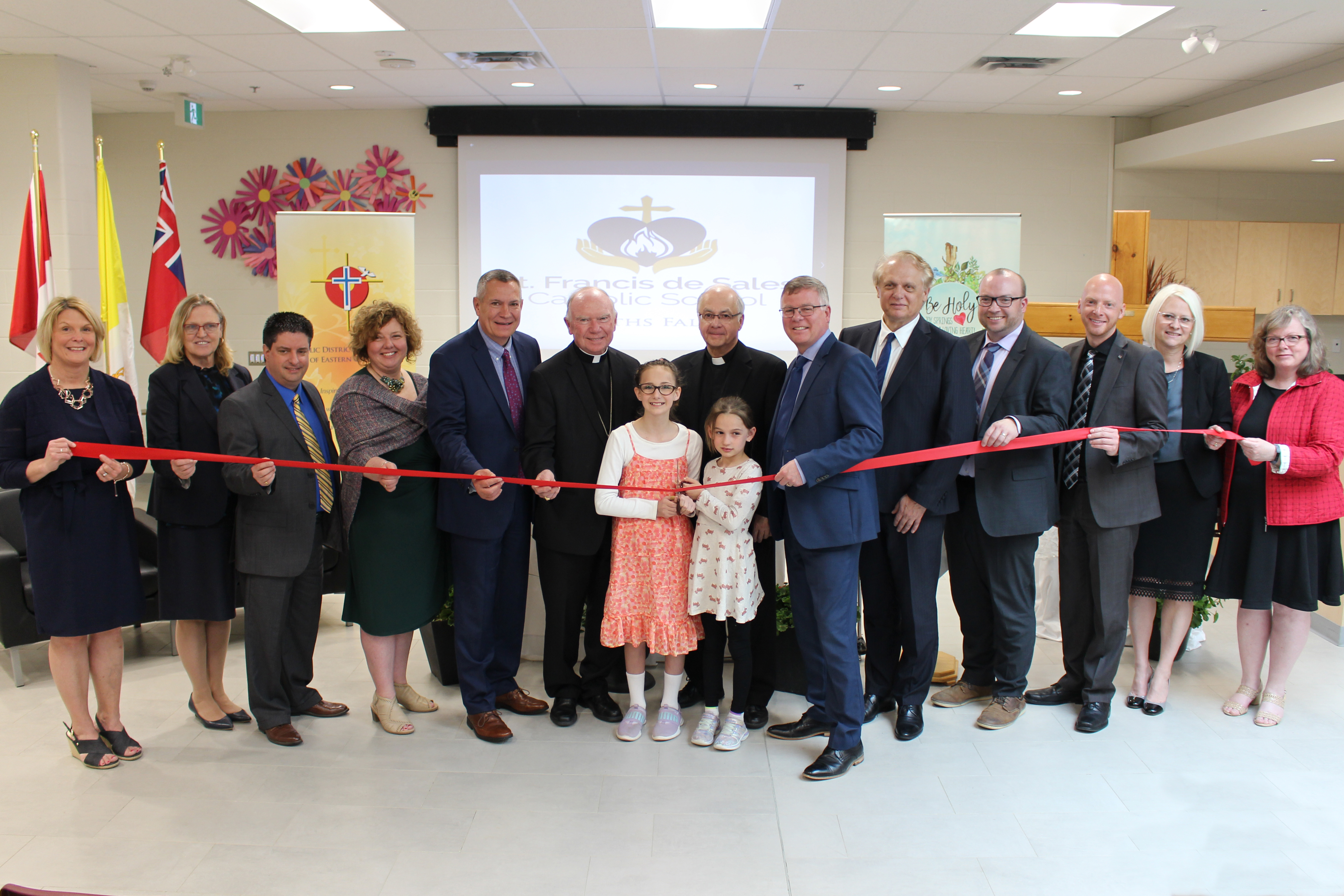 A group of staff, students, trustees and administrators cut the ribbon at the official opening of St. Francis de Sales Catholic School.