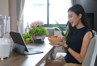 Photo of woman eating in front of laptop.