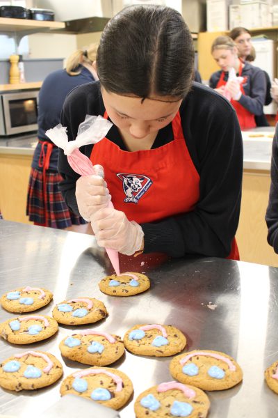 Student decorates smile cookies.
