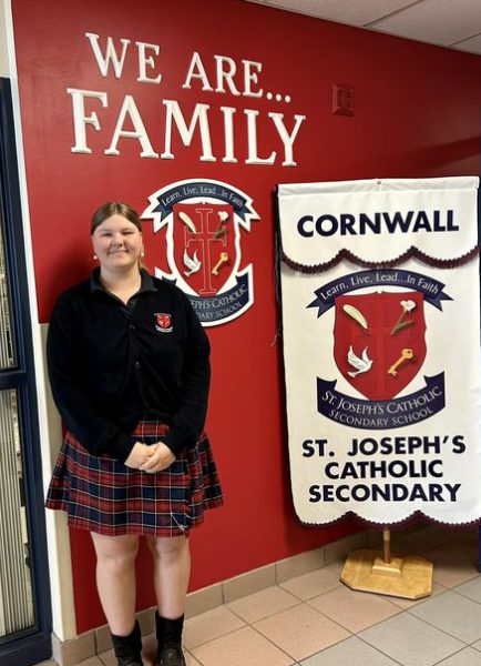 Student Isabelle Gillard stands with a St. Joseph's Catholic Secondary School banner.