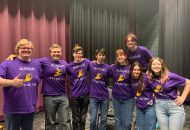 Students stand together in a line smiling.