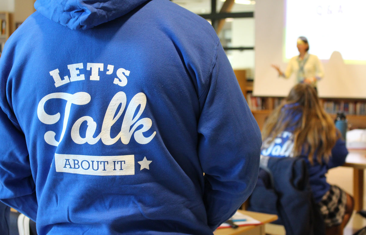 Student wearing new "Let's Talk About It" branded sweatshirt.