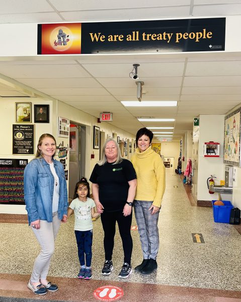 Staff and students pictured next to a new "We are all treaty people" banner in their school.